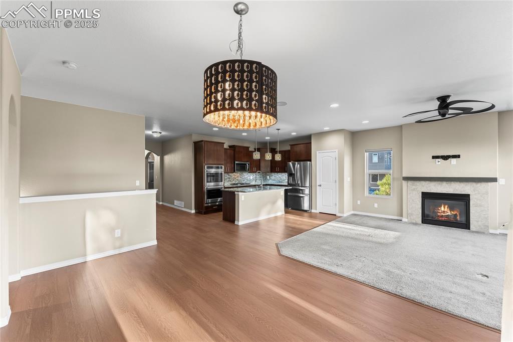Unfurnished living room featuring recessed lighting, light wood-type flooring, arched walkways, ceiling fan, and a glass covered fireplace