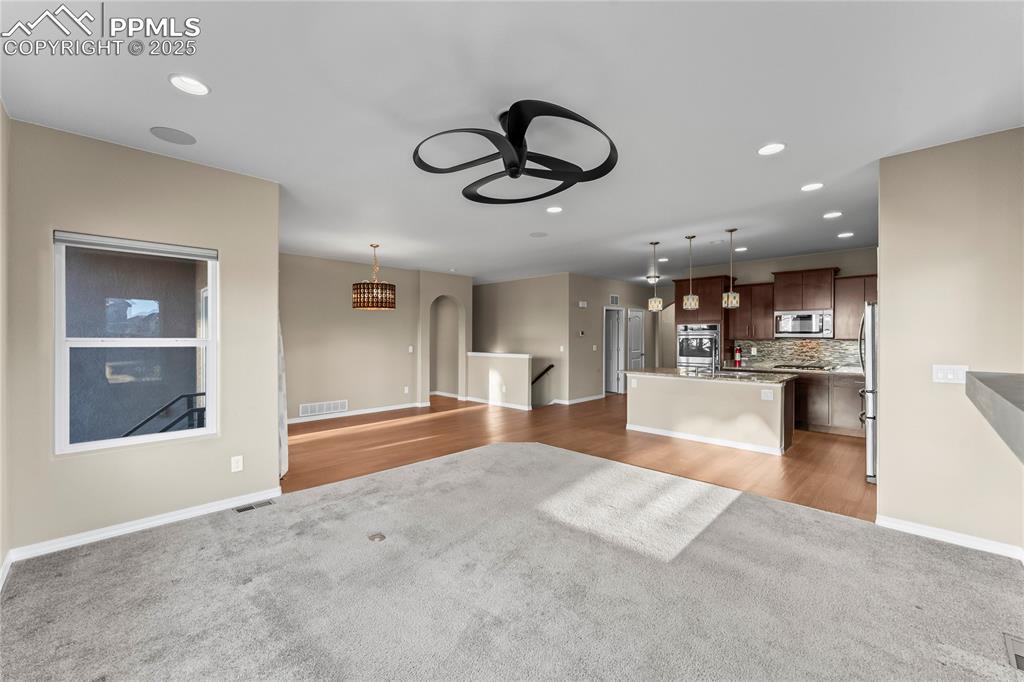 Unfurnished living room with recessed lighting, light wood-style floors, a ceiling fan, light colored carpet, and arched walkways