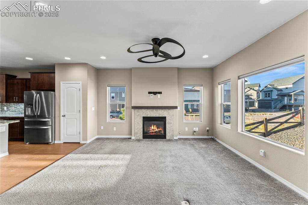 Unfurnished living room featuring recessed lighting, a ceiling fan, a tile fireplace, and light colored carpet
