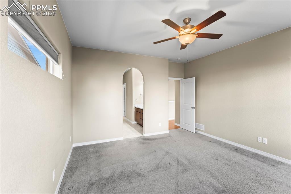 Spare room with light colored carpet, arched walkways, and ceiling fan