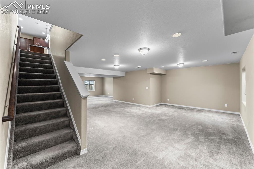 Basement with carpet, stairway, and recessed lighting