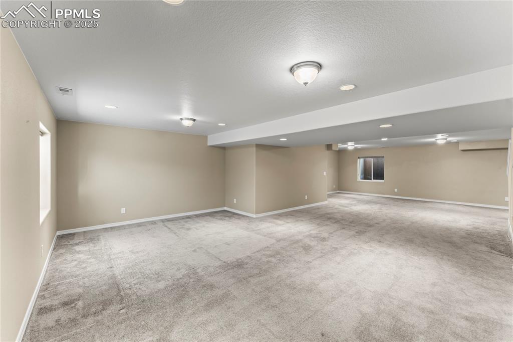 Basement with light colored carpet, recessed lighting, and a textured ceiling