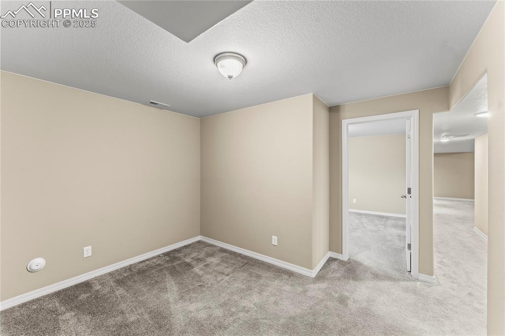 Carpeted empty room with a textured ceiling and baseboards