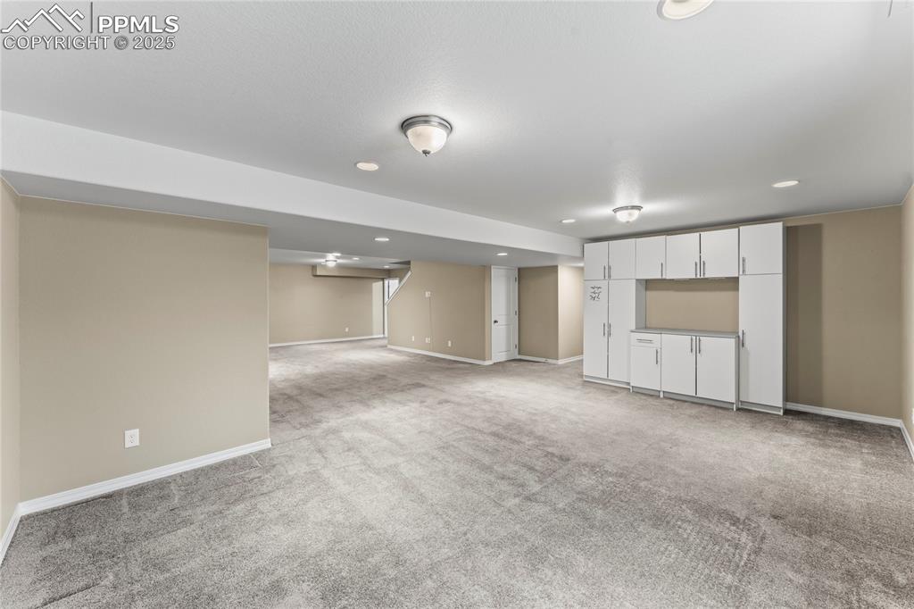 Finished below grade area with light colored carpet and recessed lighting