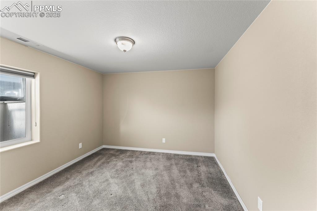 Carpeted empty room featuring baseboards and a textured ceiling
