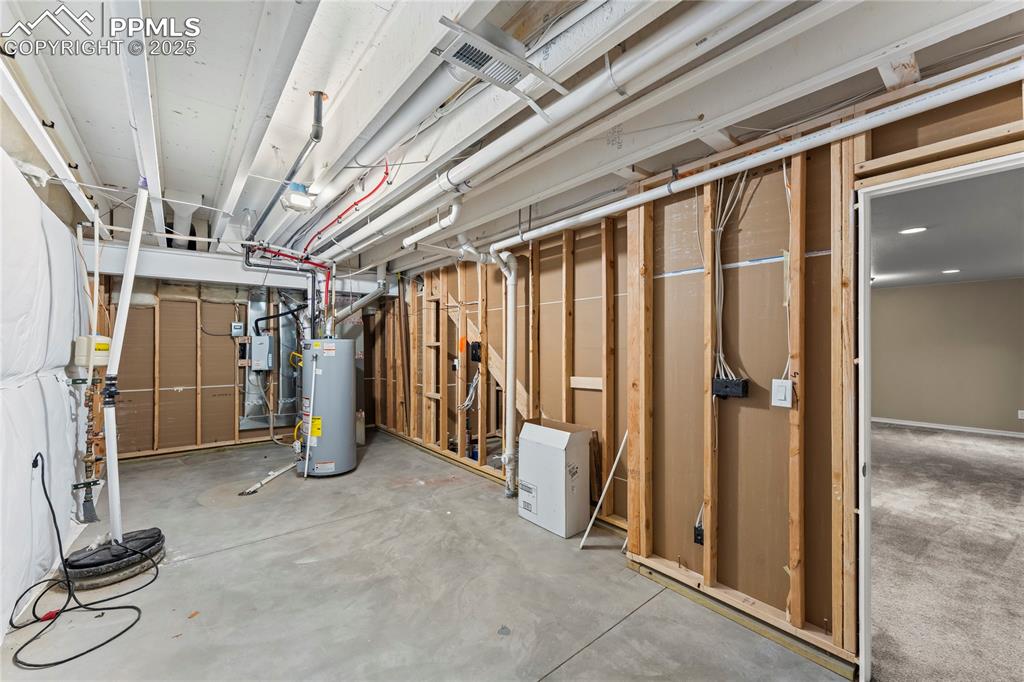 Unfinished basement featuring water heater and drainage system