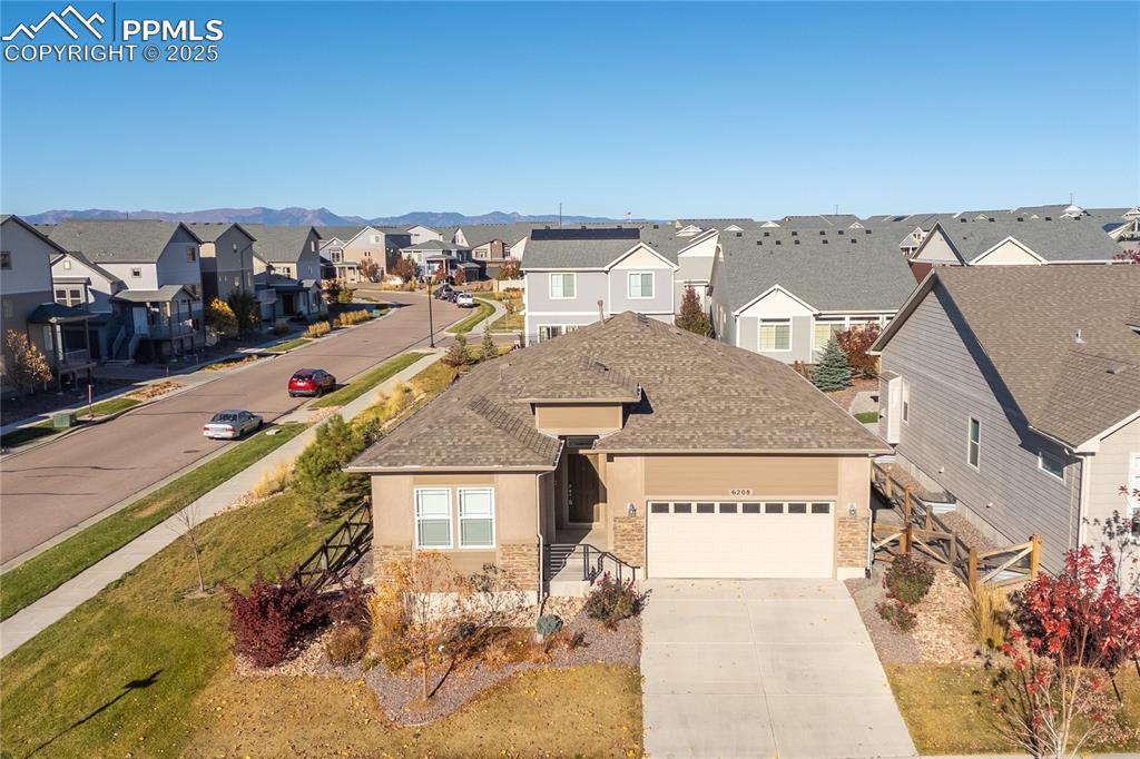 View of front of property featuring driveway, a residential view, a garage, roof with shingles, and stucco siding