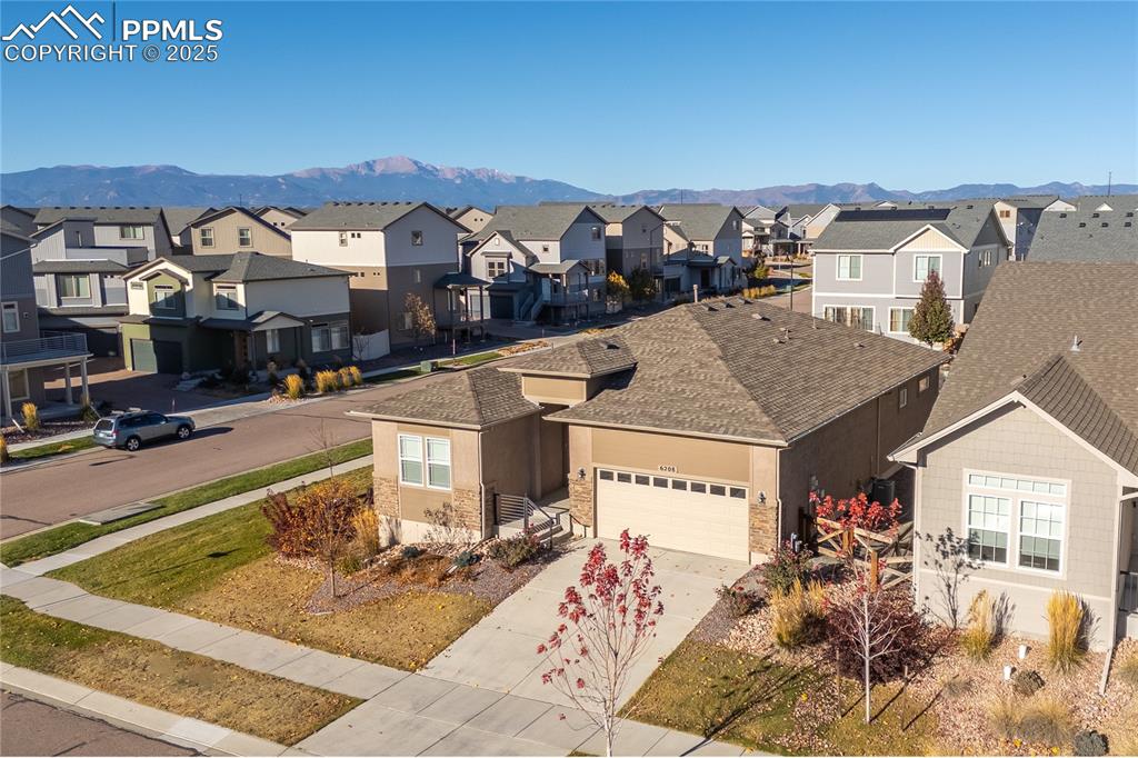 View of front of home featuring concrete driveway, a mountain view, a garage, roof with shingles, and stucco siding
