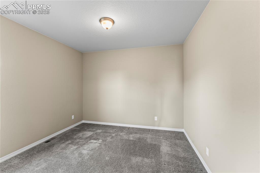 Spare room featuring carpet and baseboards