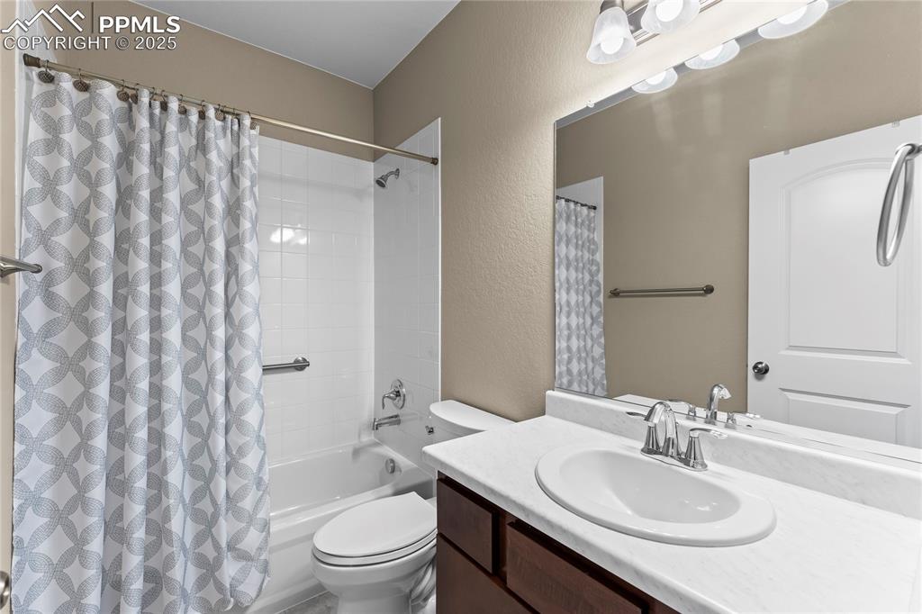 Bathroom featuring a textured wall, vanity, and shower / bath combination with curtain