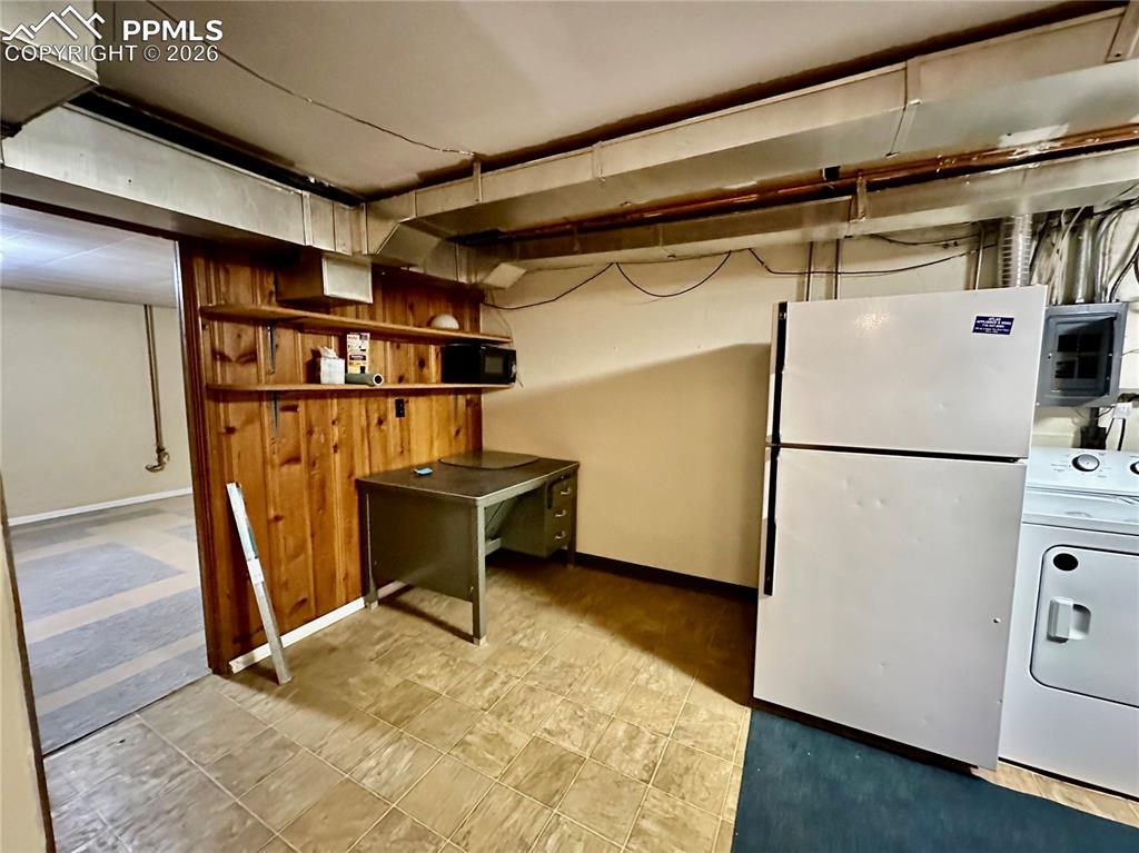 Finished basement featuring freestanding refrigerator, washer / dryer, and light flooring
