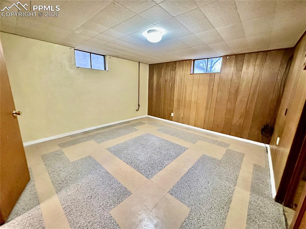 Below grade area with light floors, plenty of natural light, and wooden walls