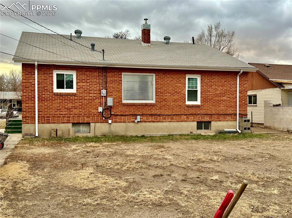 View of property exterior with brick siding, roof with shingles, and a chimney