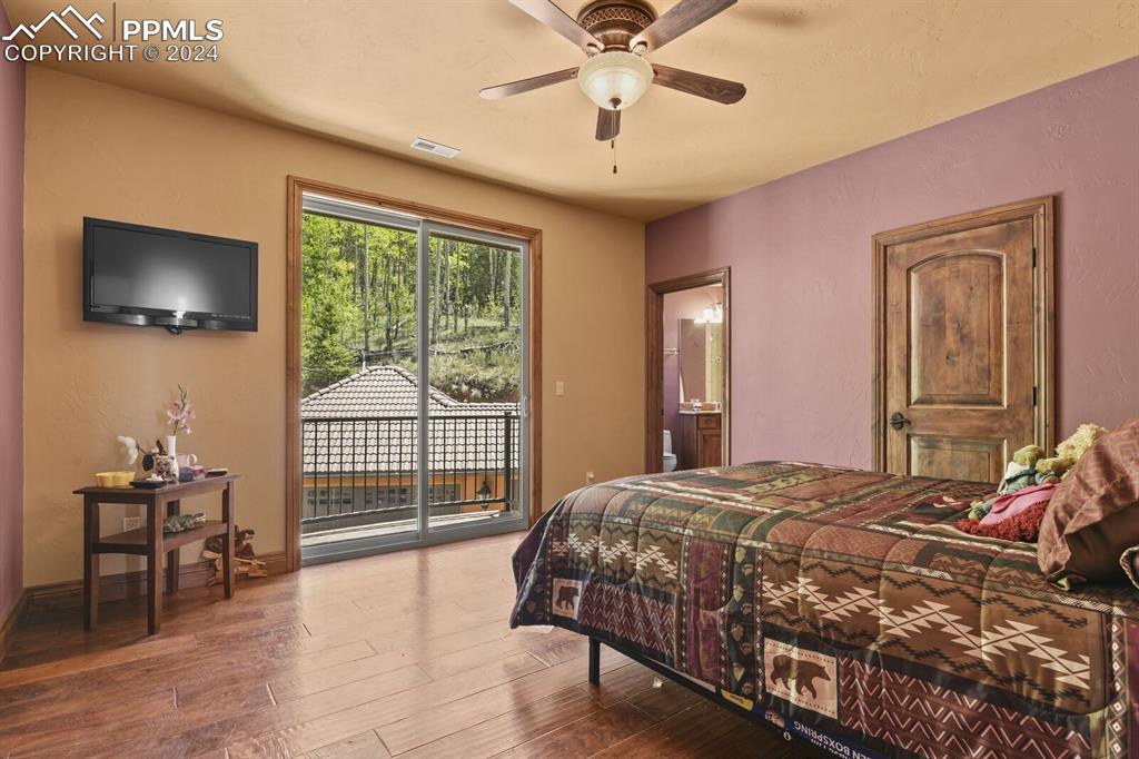 Bedroom with ensuite bathroom, access to exterior, ceiling fan, and hardwood / wood-style floors