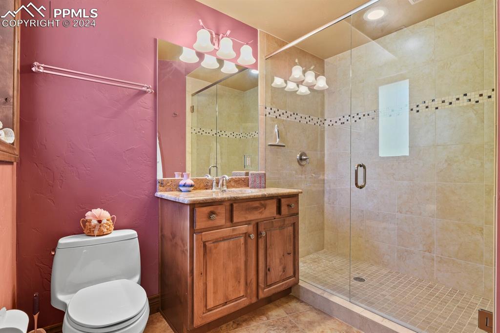 Bathroom with tile floors, walk in shower, vanity, and toilet