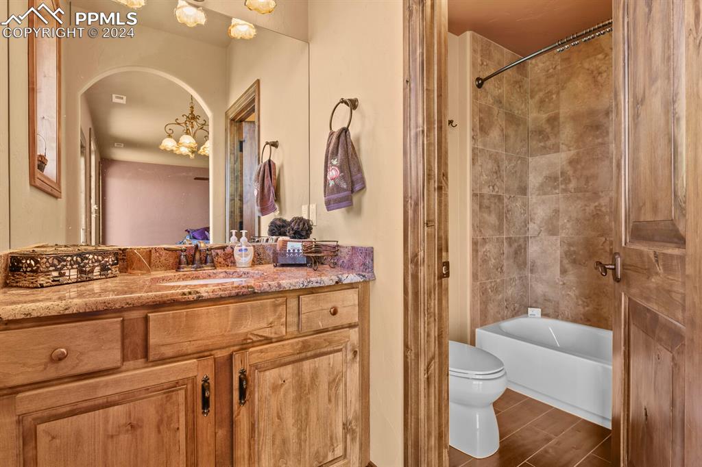 Full bathroom featuring tile walls, a chandelier, tiled shower / bath combo, vanity, and toilet