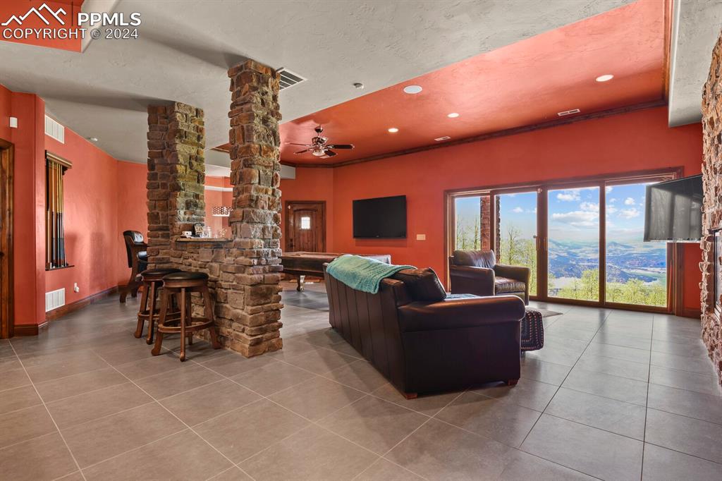 Tiled living room with ceiling fan and decorative columns