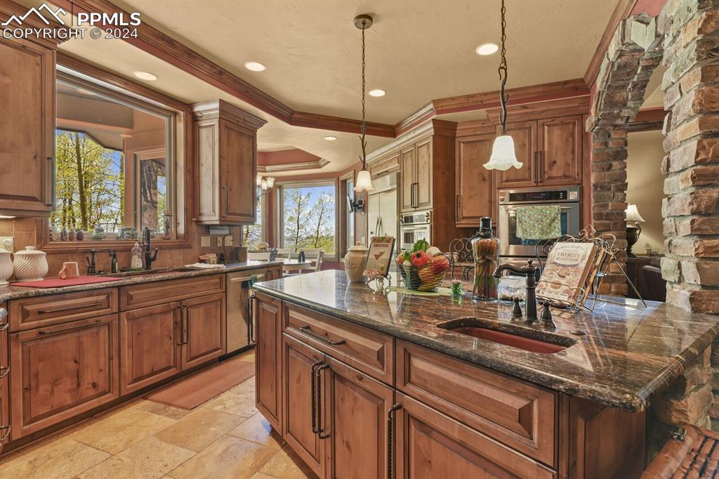 Kitchen featuring stainless steel appliances, light tile flooring, hanging light fixtures, sink, and ornamental molding