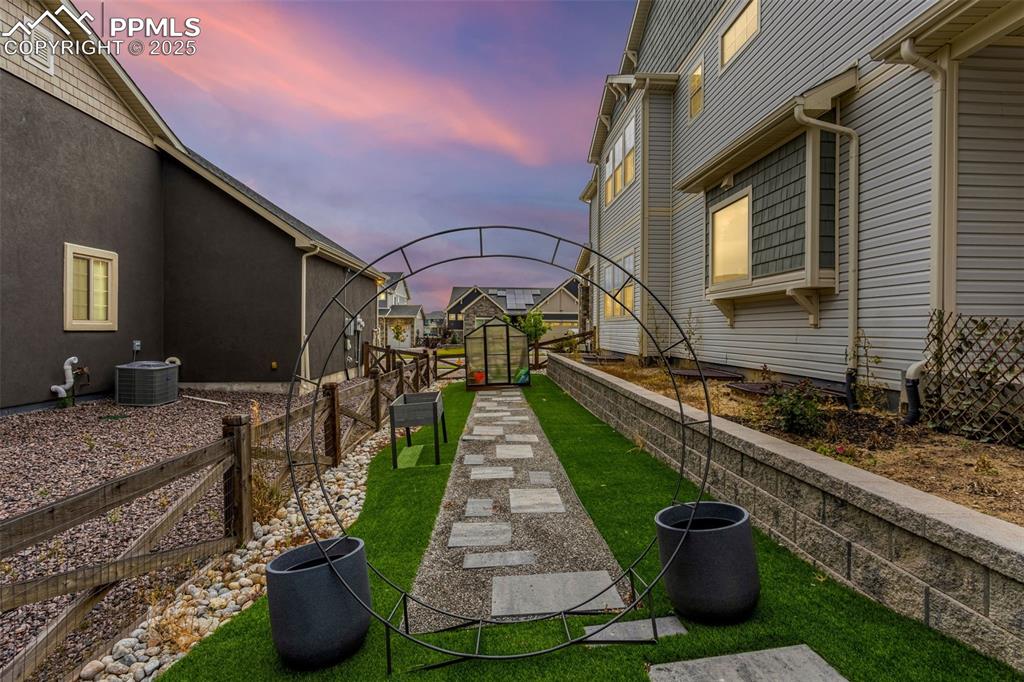 Circular metal garden trellis is the entry to the custom walkway leading to perfectly-sized greenhouse!