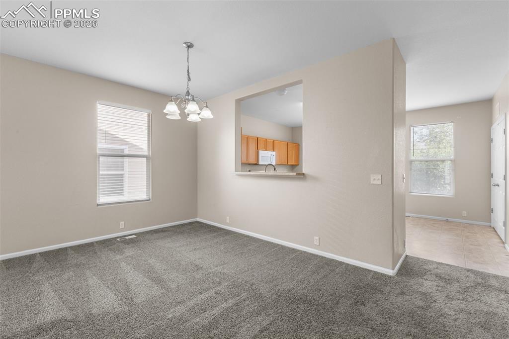 Unfurnished dining area with light carpet and a chandelier
