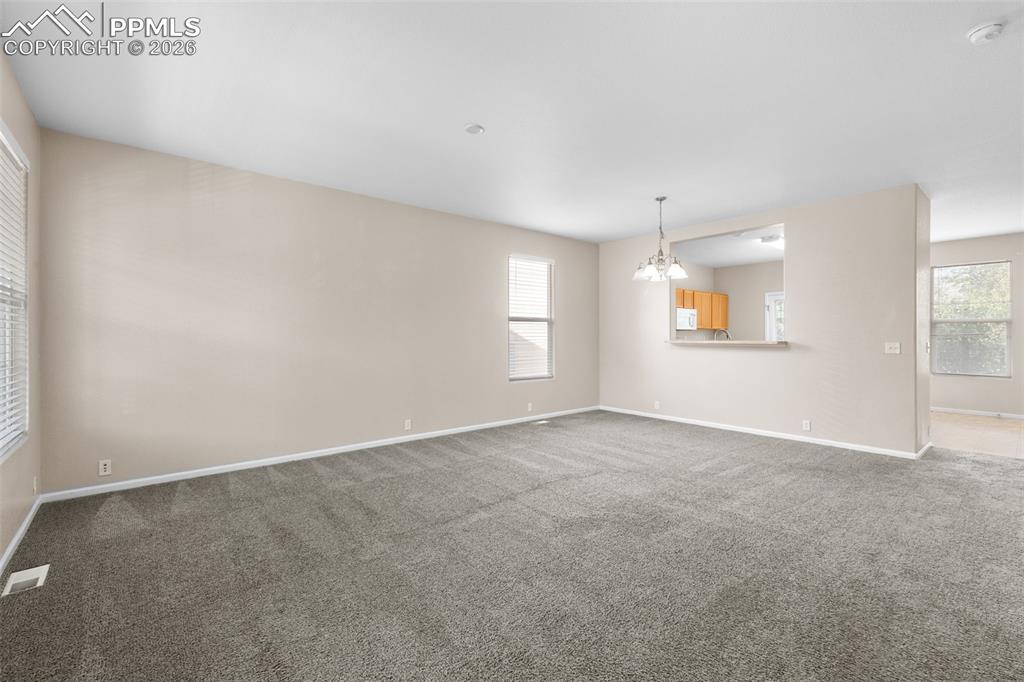 Unfurnished living room featuring carpet and a chandelier