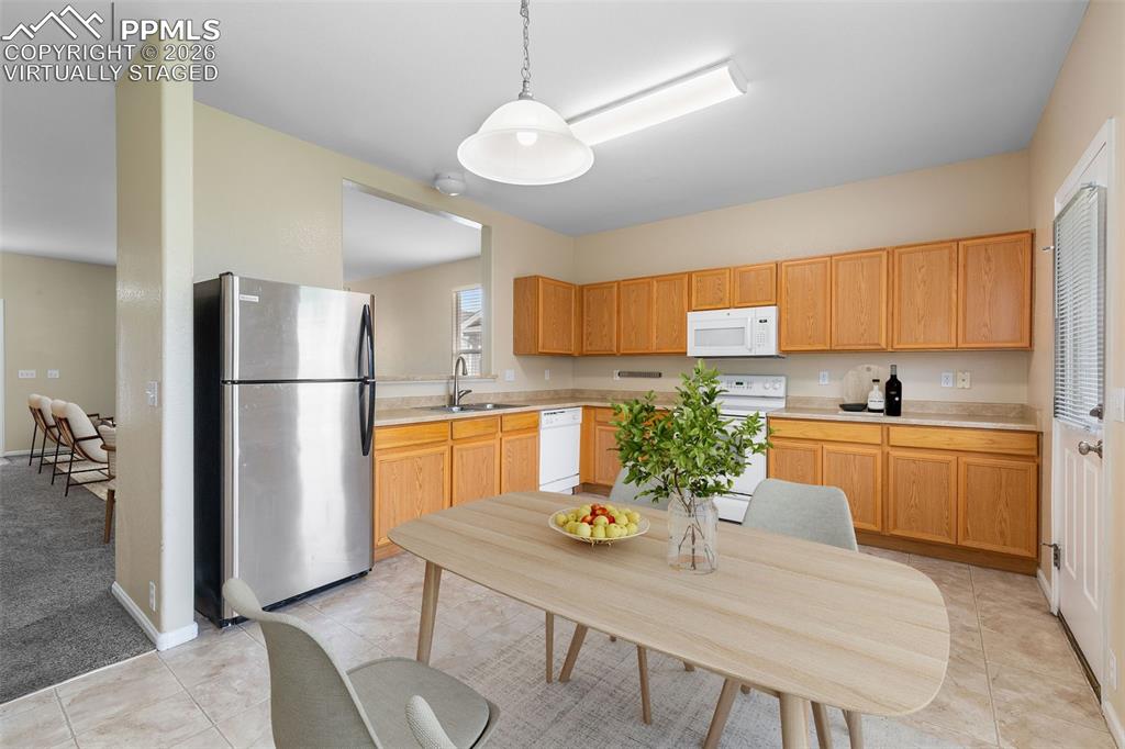 *Virtually Staged* Kitchen featuring white appliances, light countertops, decorative light fixtures, and light carpet