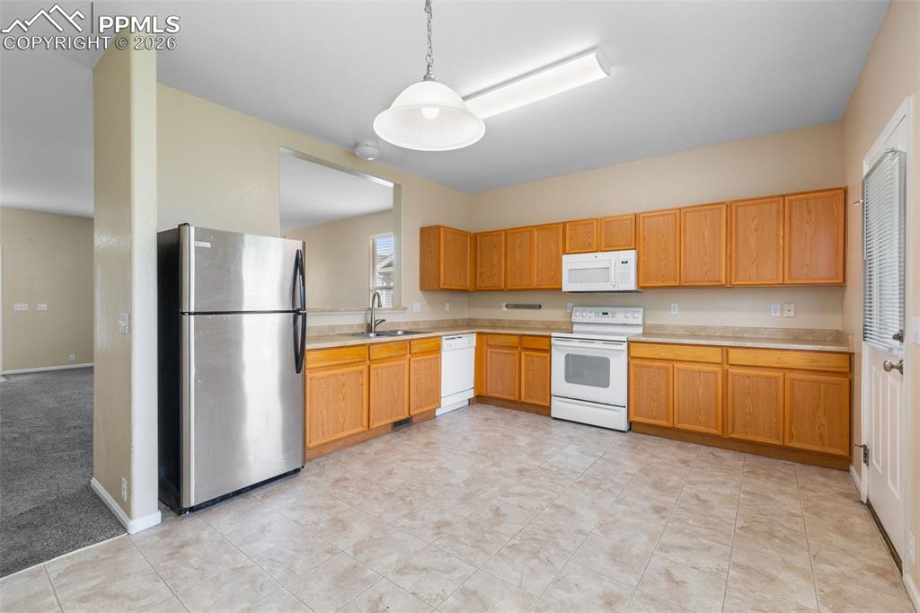 Unfurnished Kitchen with white appliances, light countertops, and hanging light fixtures