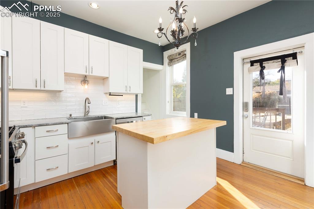 Kitchen featuring butcher block countertops, white cabinetry, backsplash, light wood-style flooring, and recessed lighting