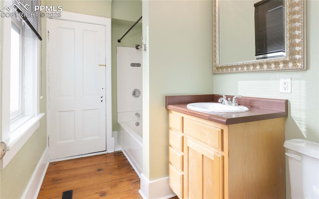 Bathroom with vanity, bathing tub / shower combination, light wood-style flooring, and plenty of natural light