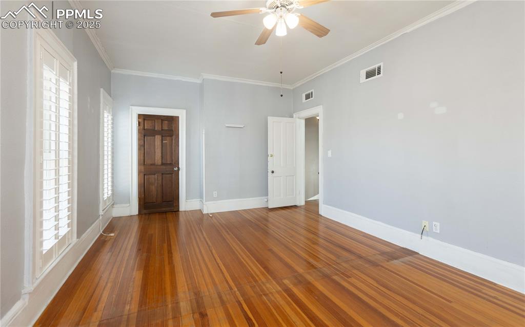 Unfurnished bedroom with crown molding, ceiling fan, and hardwood / wood-style floors