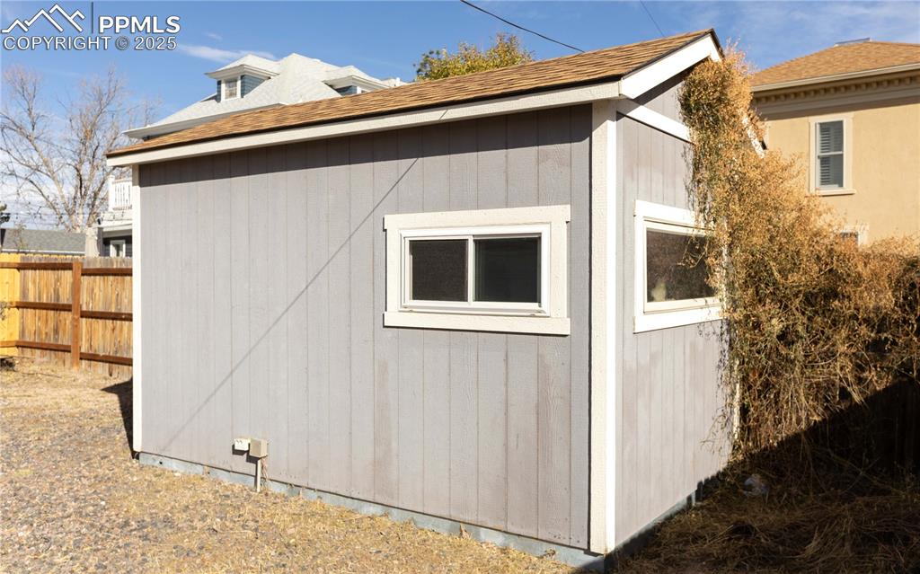 View of side of home with an outdoor structure and roof with shingles