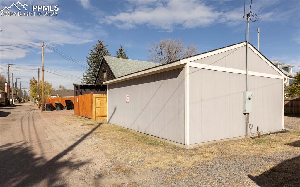 View of property exterior featuring an outbuilding and roof with shingles