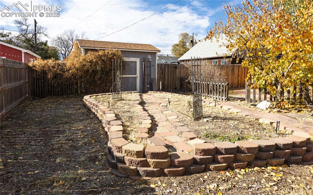Fenced backyard featuring a storage shed and a patio area