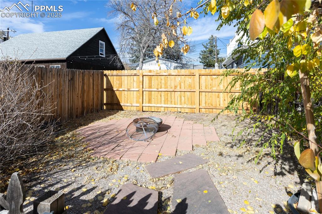 Fenced backyard with an outdoor fire pit and a patio
