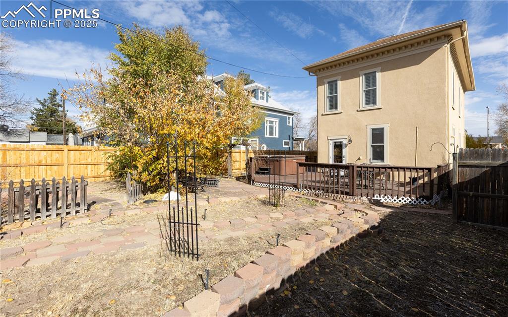 Rear view of house with stucco siding, a fenced backyard, and a wooden deck