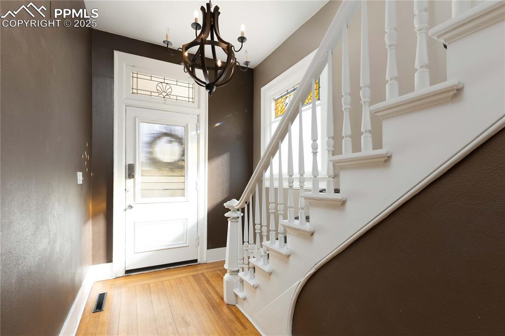 Entrance foyer with light wood-style flooring, a chandelier, and stairs