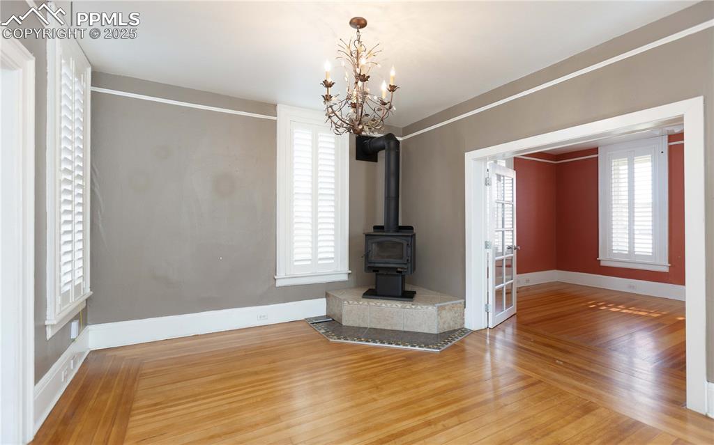 Unfurnished living room featuring wood finished floors and a wood stove