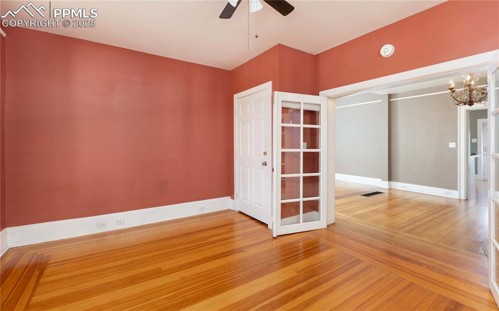 Empty room with light wood-style floors, a chandelier, and ceiling fan