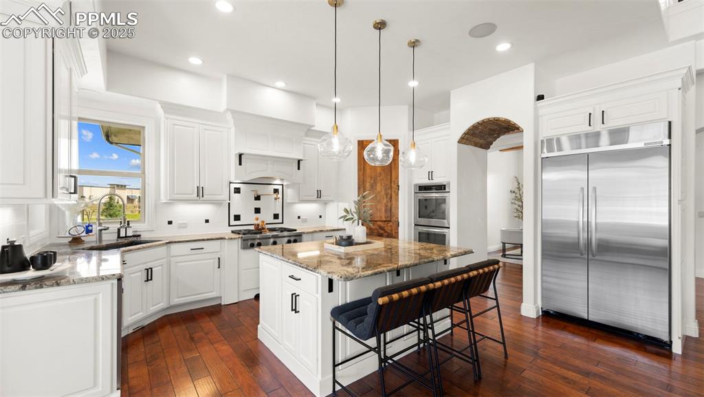 Kitchen featuring light stone countertops, stainless steel appliances, white cabinets, dark wood-style flooring, and recessed lighting