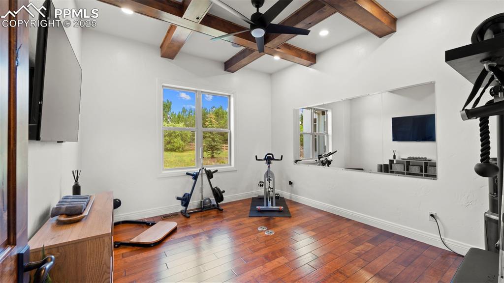 Exercise area with hardwood / wood-style floors, a ceiling fan, and coffered ceiling