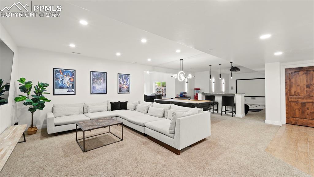 Living area with recessed lighting, light colored carpet, and a chandelier