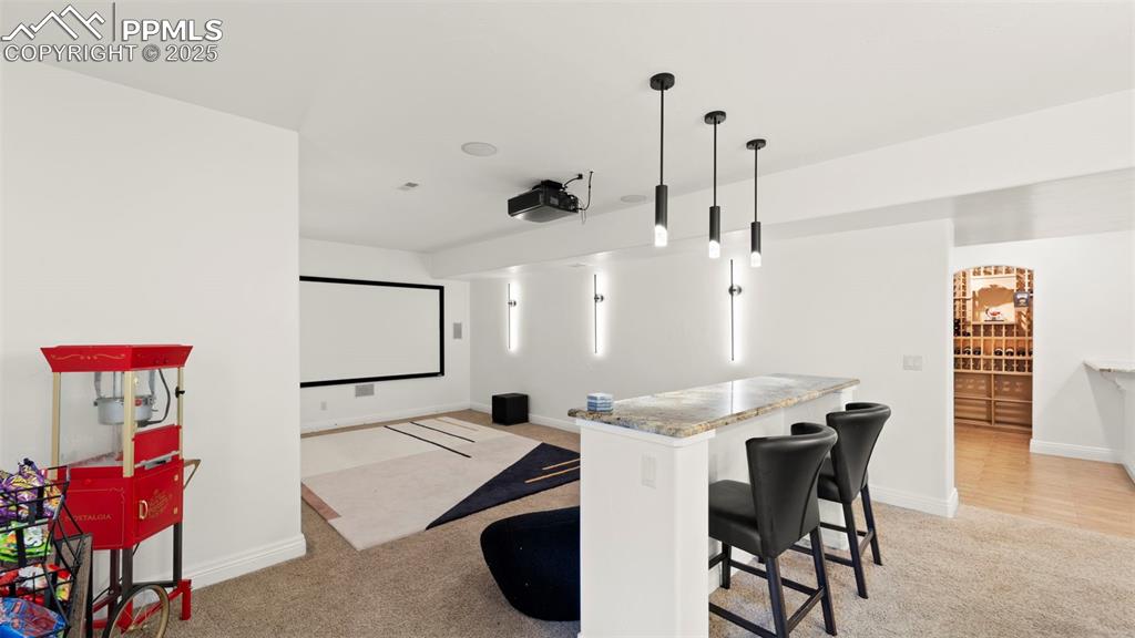 Home theater featuring light colored carpet and baseboards