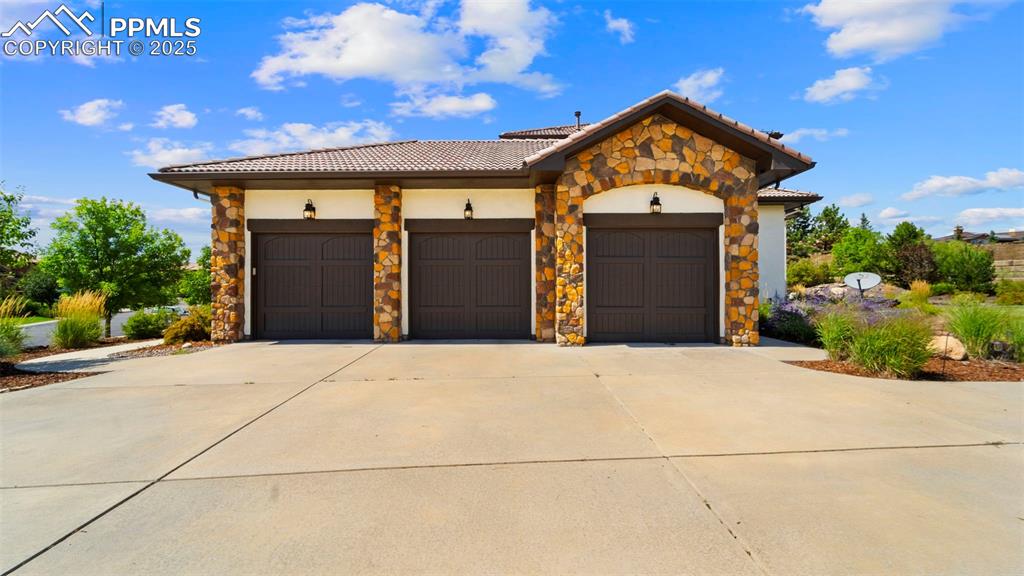 Mediterranean / spanish home with concrete driveway, stone siding, a garage, a tiled roof, and stucco siding