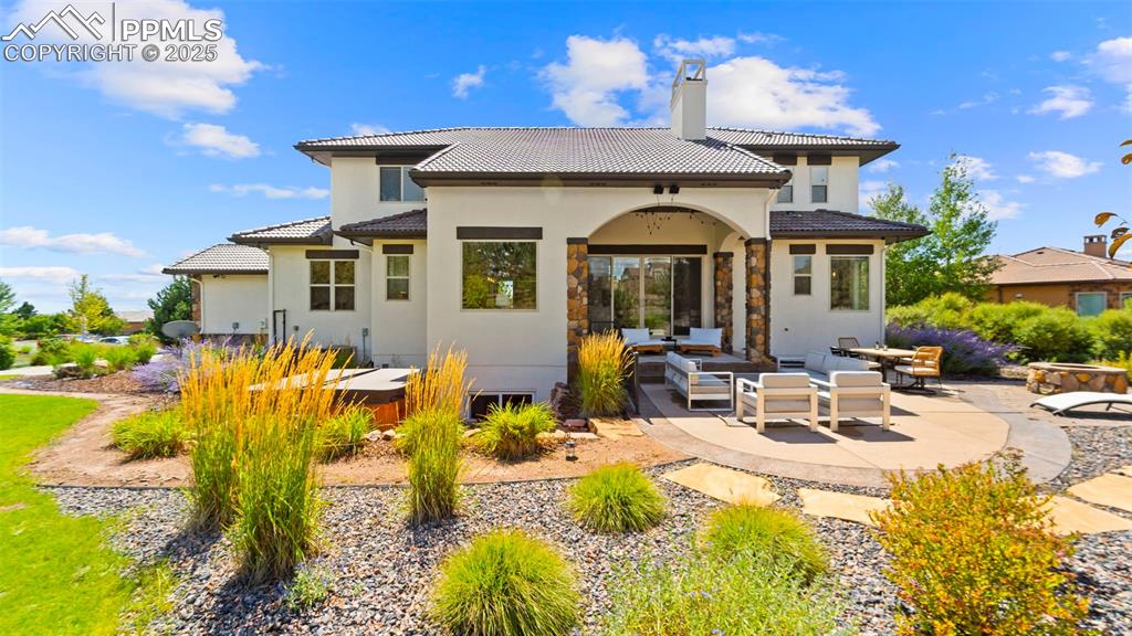 Back of property featuring a patio, outdoor lounge area, a chimney, stucco siding, and a tile roof