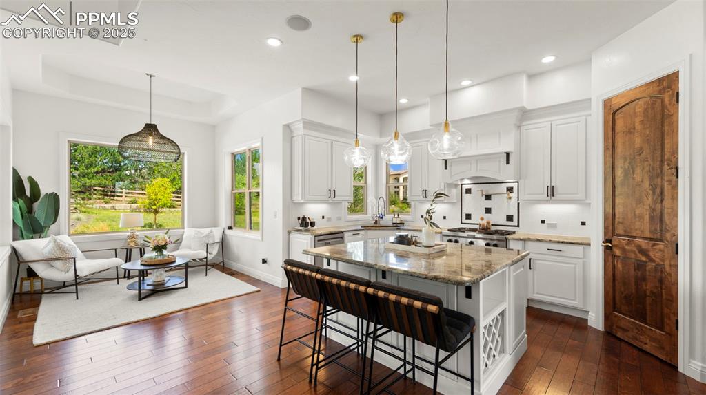 Kitchen featuring white cabinets, light stone countertops, a breakfast bar area, dark wood finished floors, and recessed lighting
