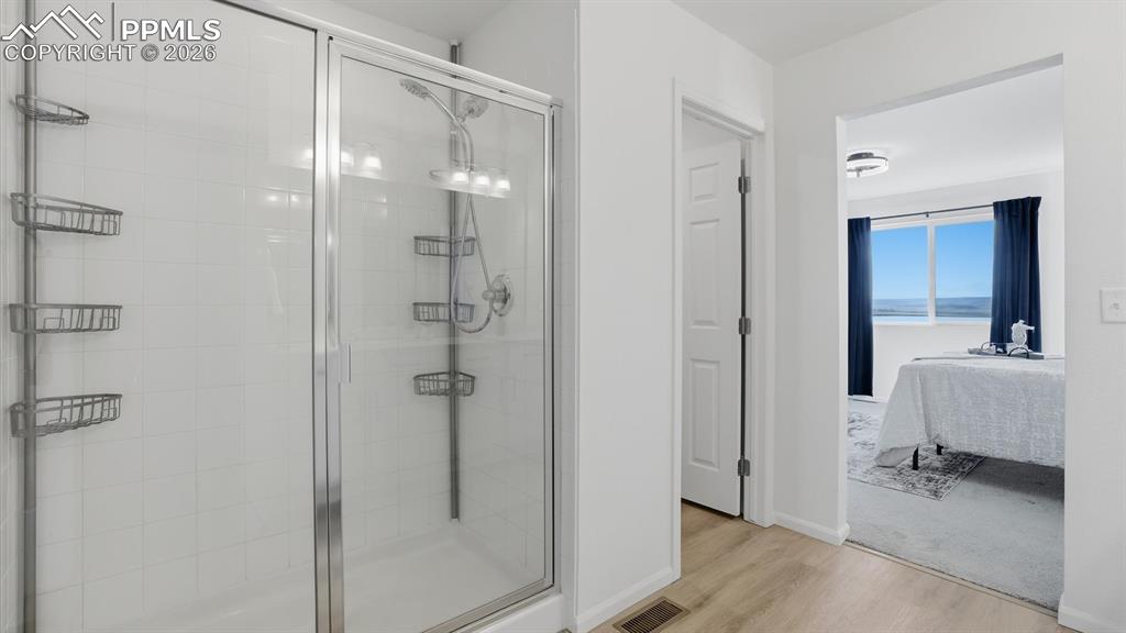 Enclosed shower in the Primary Bathroom with view into the Primary Bedroom.