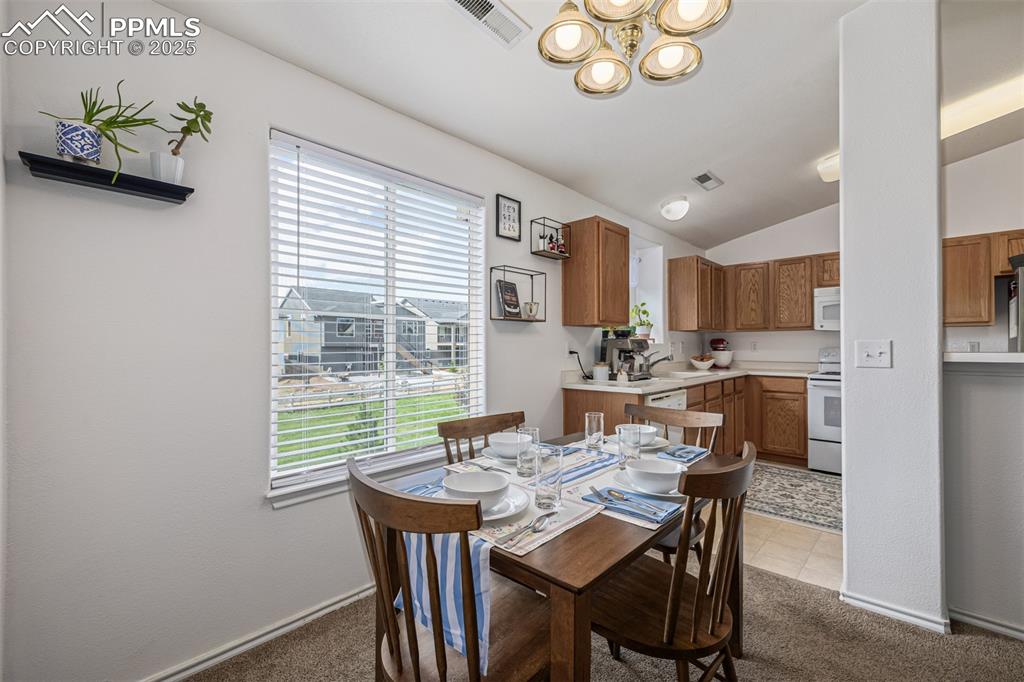 Dining room featuring light colored carpet, lofted ceiling, and light tile patterned floors
