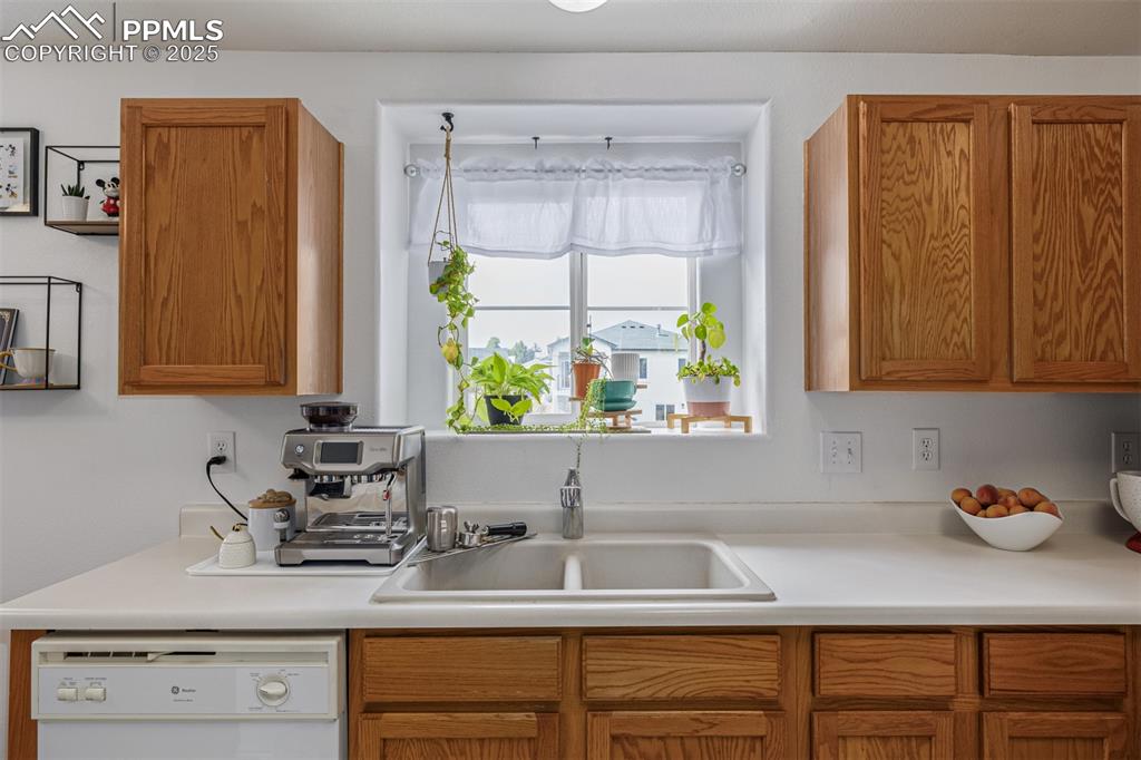 Kitchen featuring light countertops, dishwasher, and brown cabinetry