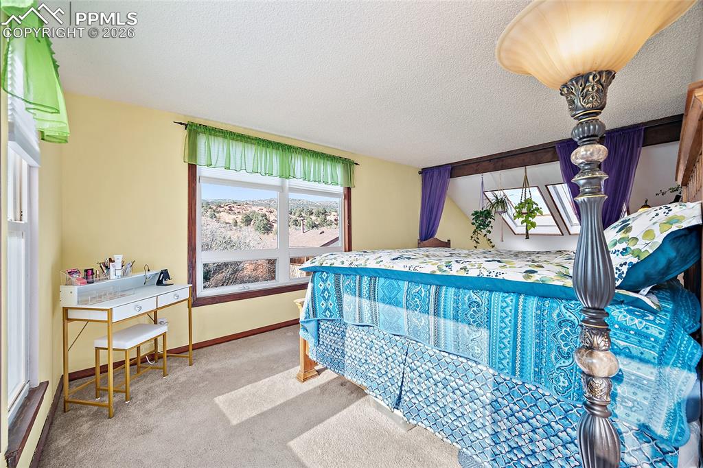 Master bedroom with a view of window and red rocks outside. Skylights off to the right with views of the red rocks.