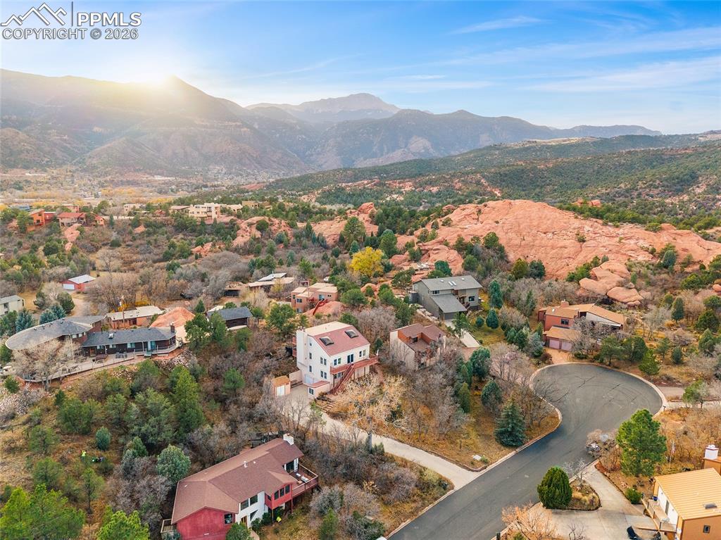 Far shot of property and driveway with Front Range and Pike's Peak in the background and surrounding red rocks.